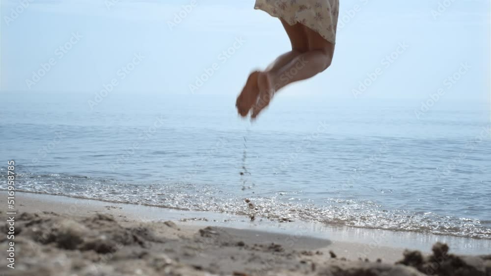 Bare woman feet jumping in ocean water close up. Girl have fun bouncing