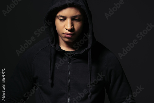 African american hooligan in hoodie standing isolated on black
