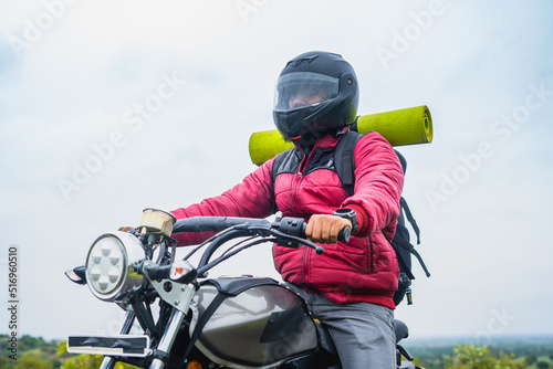 Rider with backback on bike traveling with helmet - concept of explorer, vacations and holidays