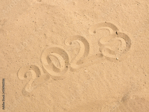 The year 2023  written on the sand of the beach  is a New Year s greeting card for travel