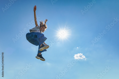 Outdoor photo of young caucasian teenager jump with blue sky background. photo