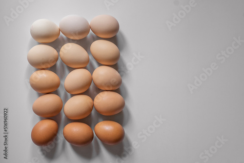 Eggs of different shades of brown lie in a gradient color on a light gray background, flatlay