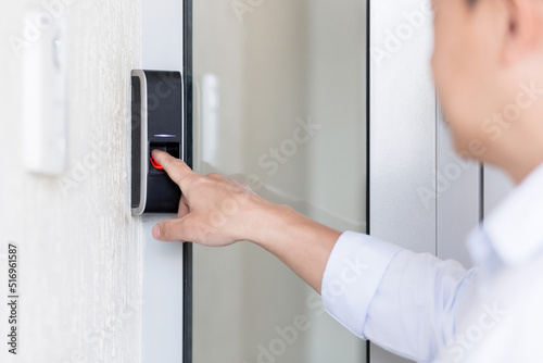 Close-up photo. The hand of a young man in a white shirt calls the intercom of the house, presses the button, waits for the door to open.