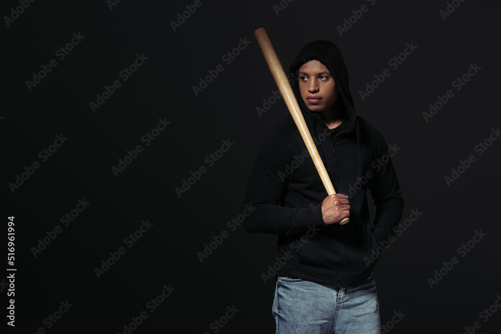 African american hooligan with baseball bat looking away isolated on black African american hooligan with baseball bat looking away isolated on black