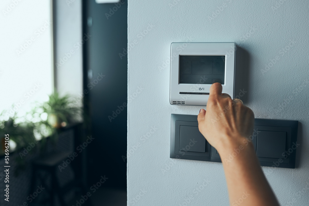 Fototapeta premium Woman controlling office with digital touch screen panel installed on the wall in office. Concept of smart remote control. Managing system at work
