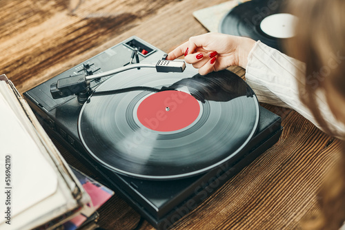 Young woman listening to music from vinyl record player. Playing music on turntable player. Female enjoying music from old record collection at home