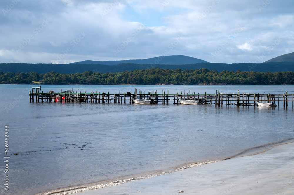 Tasman peninsula Australia, view of bay with wooden pier and moored boats in foreground
