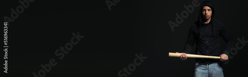 African american hooligan holding baseball bat isolated on black with copy space, banner