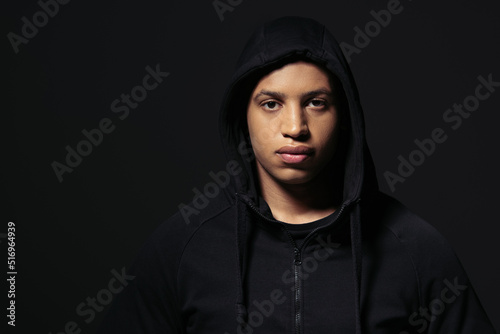 African american hooligan in hoodie looking at camera isolated on black