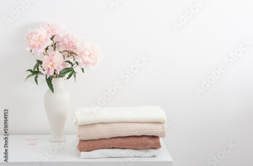 pink peonies in vase and female clothes in white room