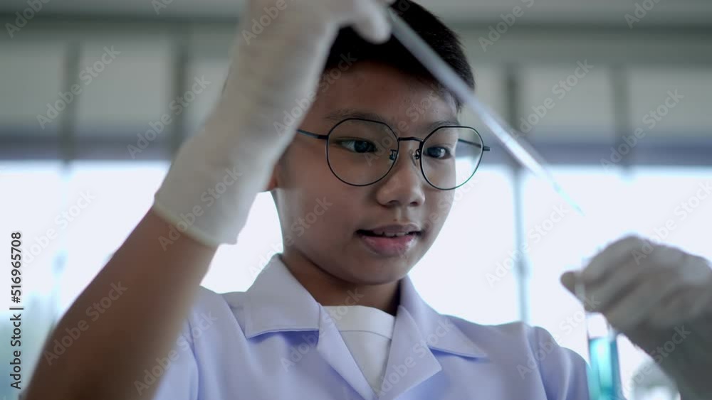 Asian boy drop blue liquid during learn chemistry at laboratory Asian boy drop blue liquid during learn chemistry at laboratory