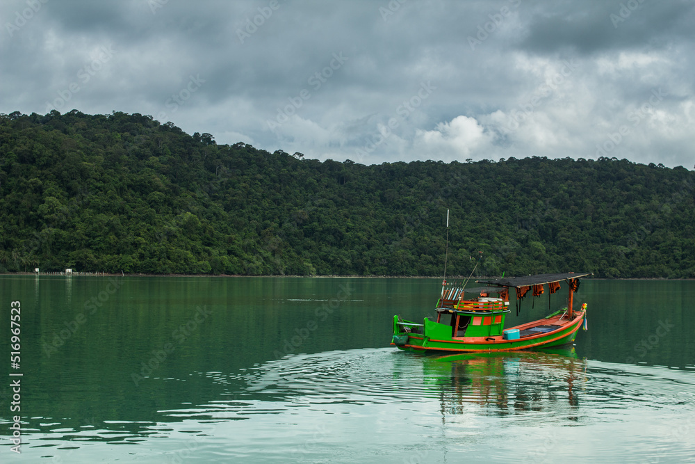 Small fishing boat in the ocean with forest island background. Small fishing boat in the ocean with forest island background.