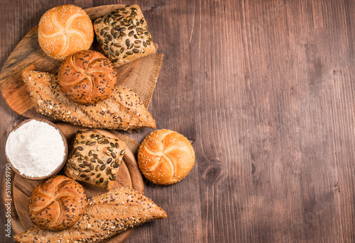 Assortment of baked bread with seeds on a wooden table background. Bakery. Food security concept.