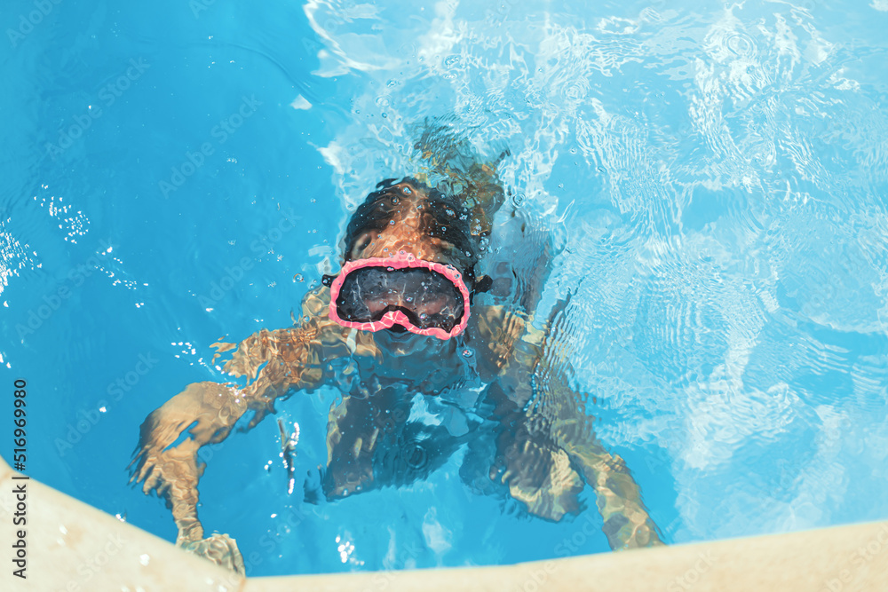 Naklejka premium Child swims in pool underwater, happy active girl in snorkel goggles has fun in water