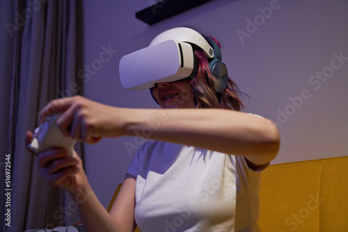 Woman with virtual reality headset and joystic is playing game. photo