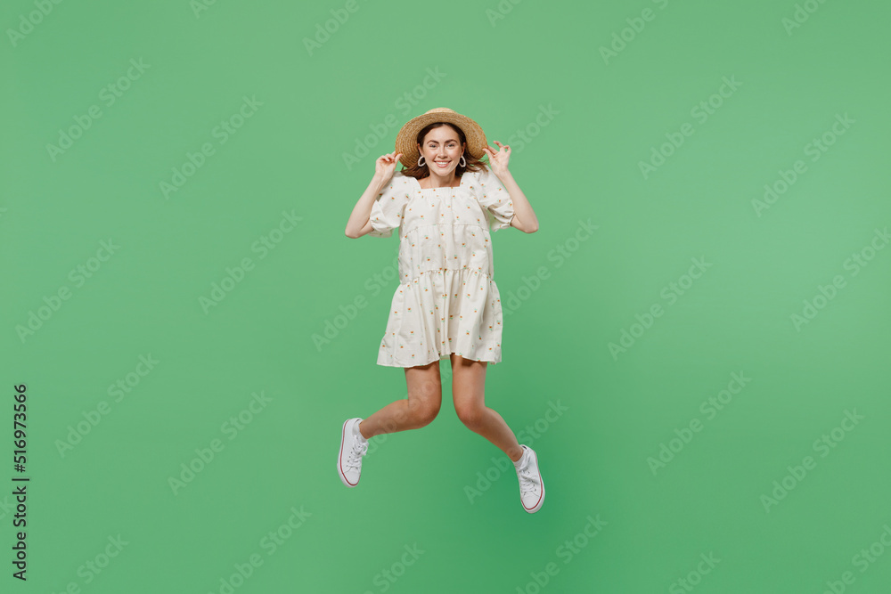 Full body young happy smiling overjoyed excited fun woman she 20s wears white dress hat jump high look camera isolated on plain pastel light green background studio portrait. People lifestyle concept.