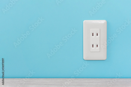 white electric outlet mounted on light blue wall. 水色の壁に取り付けられた白いコンセント