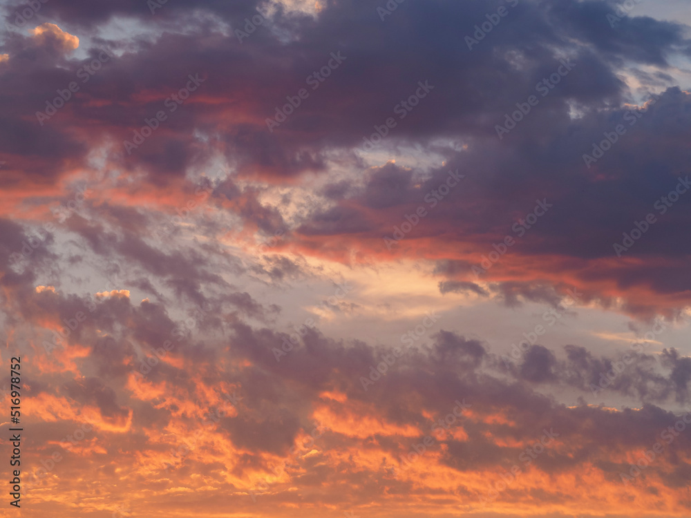 Picturesque beautiful sky as an abstraction and background. Background of a colorful sky in orange-crimson colors at dawn. Dawn cloudy sky