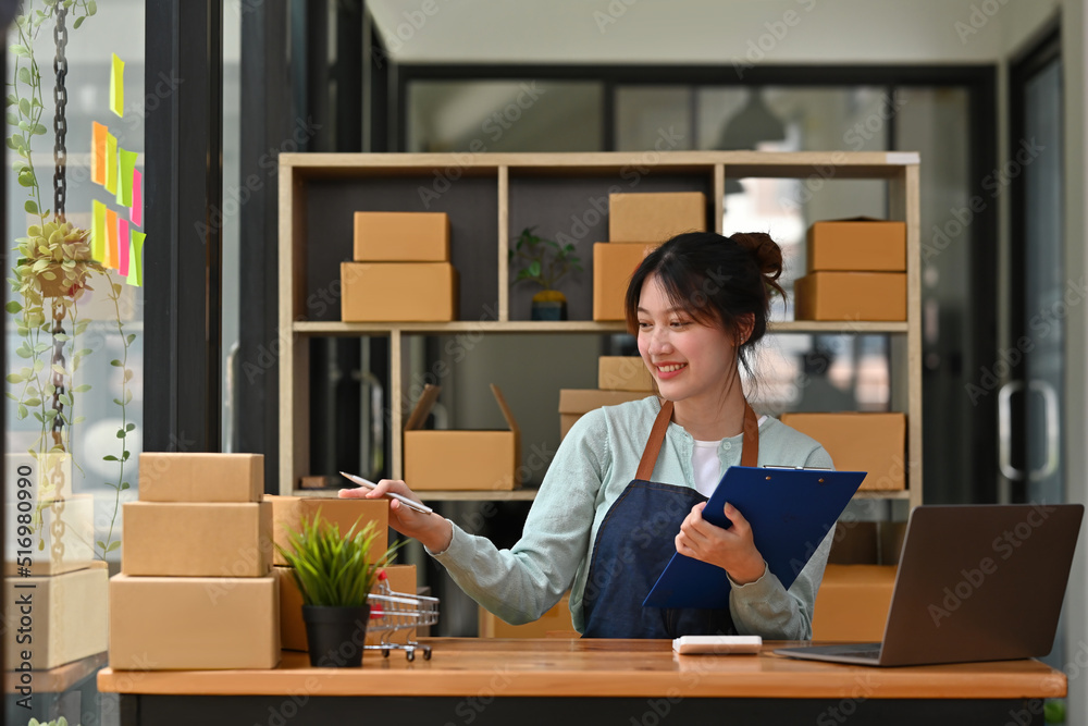 Start up small business, SME female owner checking order online to prepare to pack a box of goods for sale to customers, sme business idea. Start up small business, SME female owner checking order online to prepare to pack a box of goods for sale to customers, sme business idea.