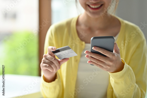 Close up with smiling female holding credit card and smartphone, Cashless society concept.