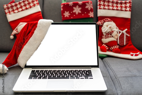 Laptop computer with white blank empty mock up screen on Merry Christmas table with presents gifts boxes in warehouse background. Ecommerce website xmas online shopping and shipping delivery, banner