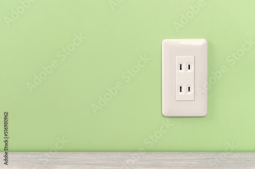 white electric outlet mounted on light green wall. 緑色の壁に取り付けられた白いコンセント