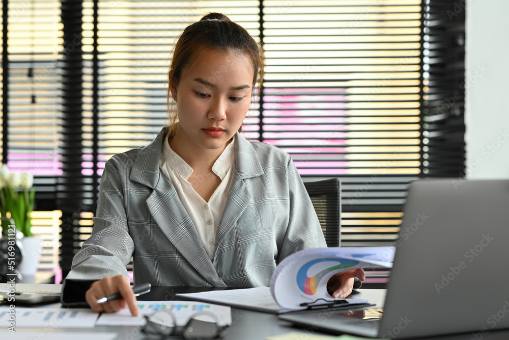 Chinese business woman working at office using a laptop and doing a business report. Chinese business woman working at office using a laptop and doing a business report.