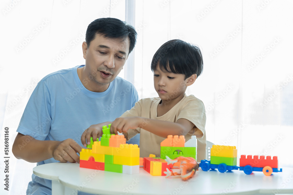Father and son at home playing the plastic block toys. Dad and and son are playing block toys Father and son at home playing the plastic block toys. Dad and and son are playing block toys