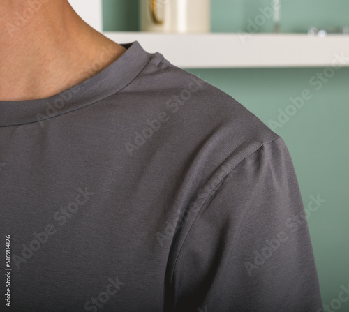 A man in a gray polo shirt on a blurry background. A man in a gray T-shirt with a loose fit close-up.The shoulder of a man in a gray T-shirt. The concept of men's clothing and fashion.A fashion model.