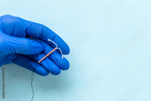 Doctor gynecologist holding intrauterine contraceptive device. T-shaped copper contraceptive photo