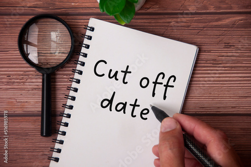 Fotografie Hand writing cut of date on notepad with table plant and magnifying glass on wooden table