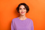 Photo of adorable thoughtful girl dressed purple pullover looking up empty space isolated orange color background