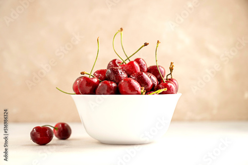 Fresh red cherries in white bowl, on neutral background. Summer delicious fruit.