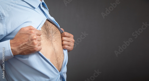 Caucasian man tearing a shirt showing hairy bare body.