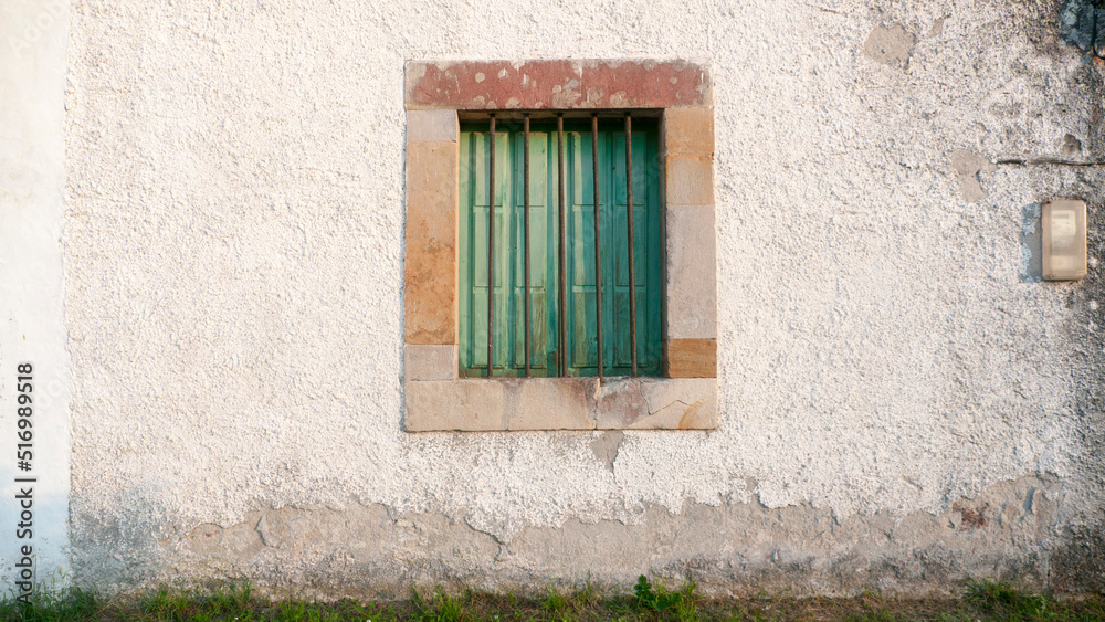 Ventana verde en fachada de casa rural