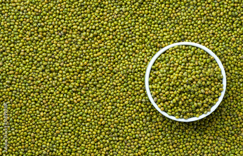 ceramic plate with raw mung beans on a mung beans background close-up top view. photo