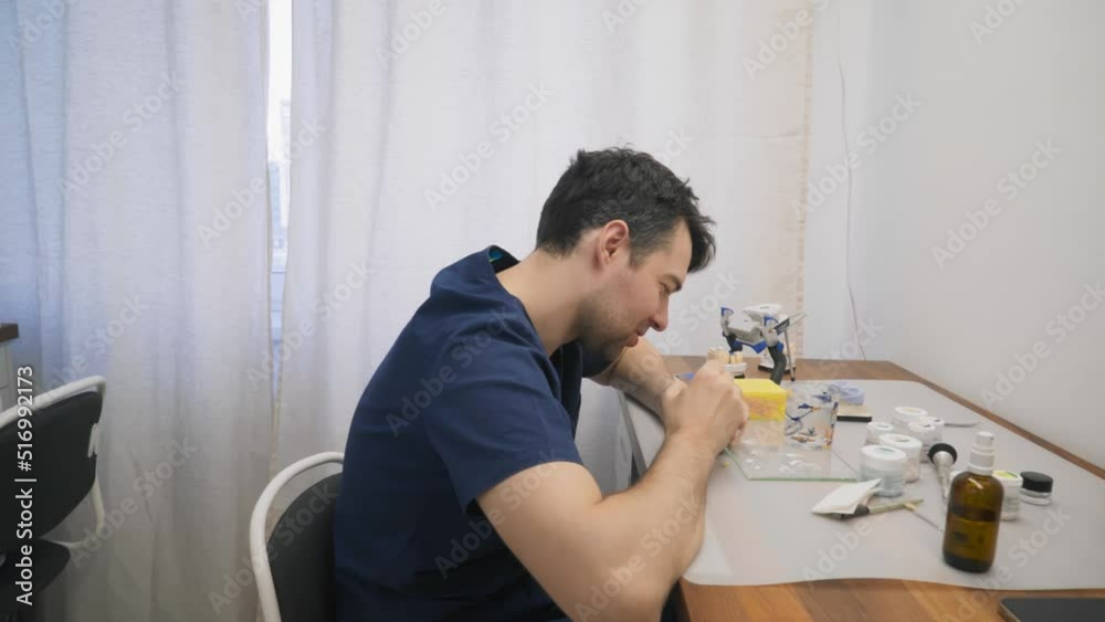 Dental laboratory technicians manufacturing the teeth implants. Technicians producing the dental replacements at the modern laboratory. Technicians create dental restorations at the laboratory.