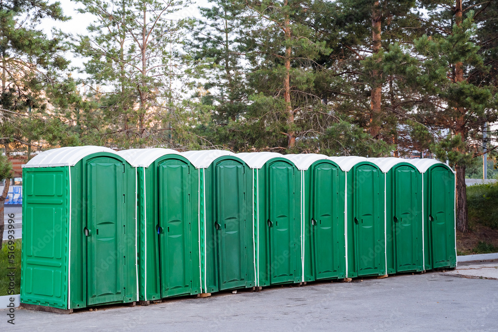 a variety of urban cabins of composting toilets, an outdoor toilet of green color, a plastic eco-toilet stands on the asphalt, a bunch of booths. a variety of urban cabins of composting toilets, an outdoor toilet of green color, a plastic eco-toilet stands on the asphalt, a bunch of booths.