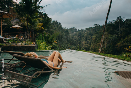 Young woman lounging at the pool side in Bali