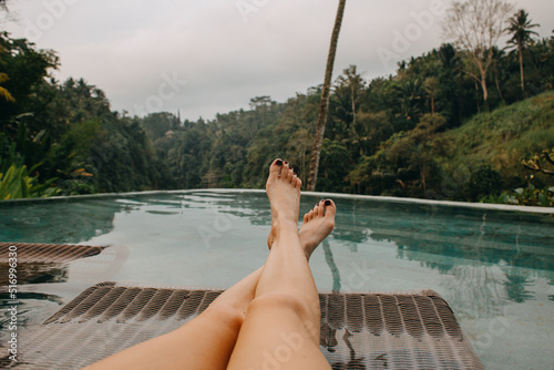 Young woman's legs lounging at the pool side