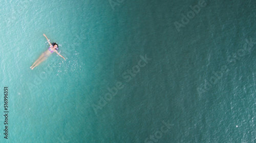 Young woman floating in pool from above