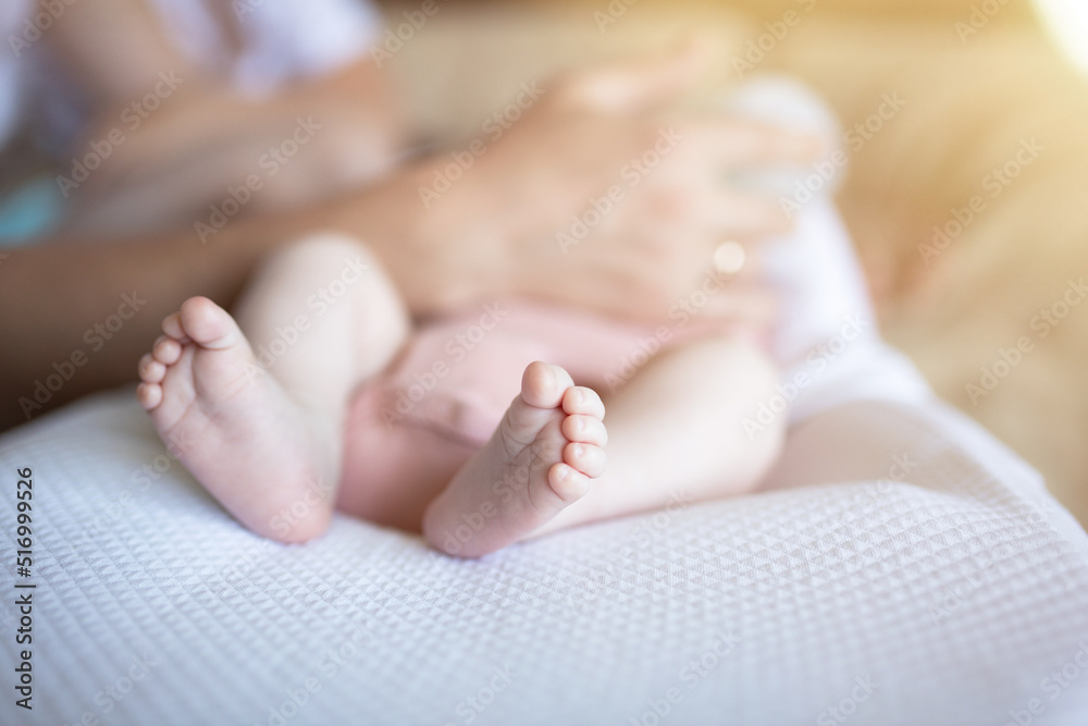 The legs of a newborn toddler lying in a Baby Cocoon and his father's arms are cut off and tenderly cared for. The father is holding bottles. Formula feed. Artificial feeding The legs of a newborn toddler lying in a Baby Cocoon and his father's arms are cut off and tenderly cared for. The father is holding bottles. Formula feed. Artificial feeding