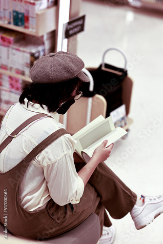 Asian women reading book by bookshelf in bookstore. Hobbies, leisure and education concept.