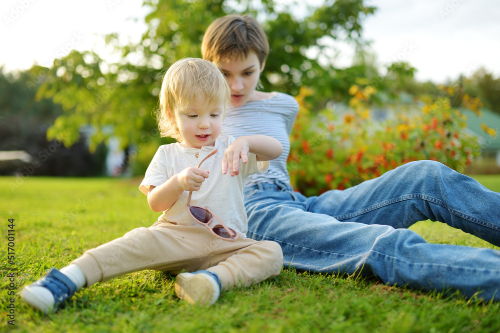 Funny toddler boy and his older sister having fun outdoors on sunny autumn day. Children exploring nature.