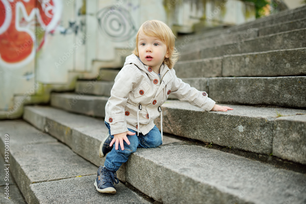 Funny toddler boy having fun outdoors on sunny autumn day. Child exploring nature. Kid walking in a city park. Funny toddler boy having fun outdoors on sunny autumn day. Child exploring nature. Kid walking in a city park.