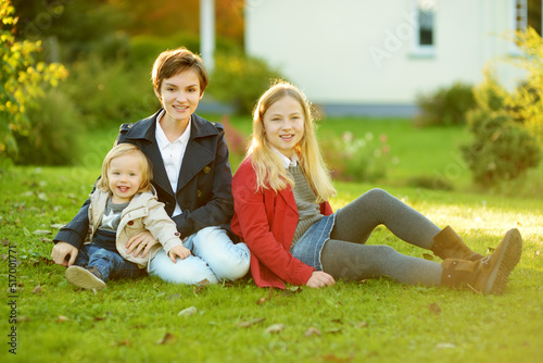 Two big sisters and their little brother having fun outdoors. Two young girls holding toddler boy on autumn day. Children with large age gap. Big age difference between siblings.