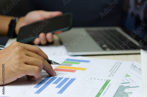 businessman holding pen to work computer graphs and charts data statistical data financial analysis documents.