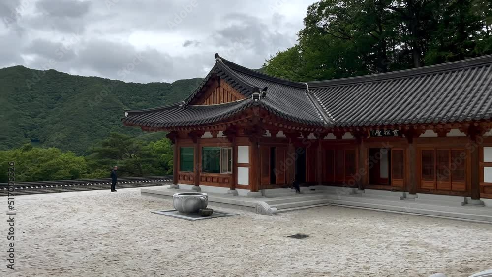 Panning shot of beautiful modern Buddhist Temple on Hilltop of with overgrown mountains in background during cloudy day - Jirisan National Park,South Korea Panning shot of beautiful modern Buddhist Temple on Hilltop of with overgrown mountains in background during cloudy day - Jirisan National Park,South Korea