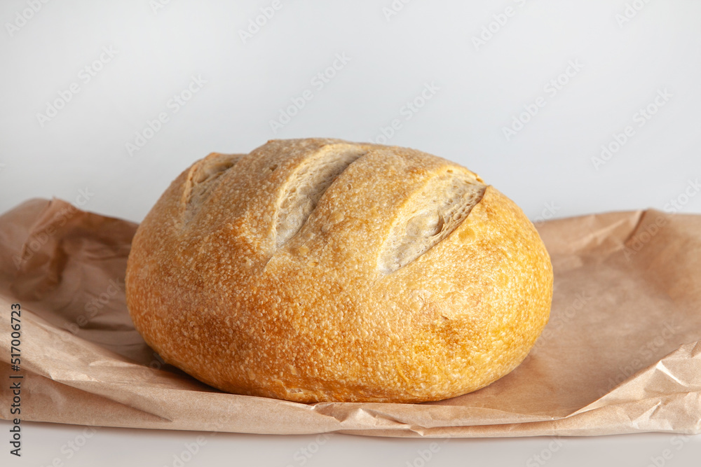 A round loaf of sourdough wheat bread lies on a paper craft bag