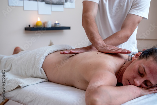 Professional therapist giving traditional Thai relaxing back massage. Deep tissue massage technique, acupressure with the palm of a hand.